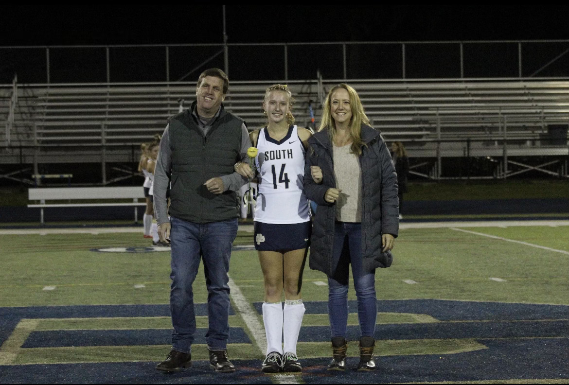 Abby Brink 24 poses with her parents on the football field during the Varsity Field Hockey senior night