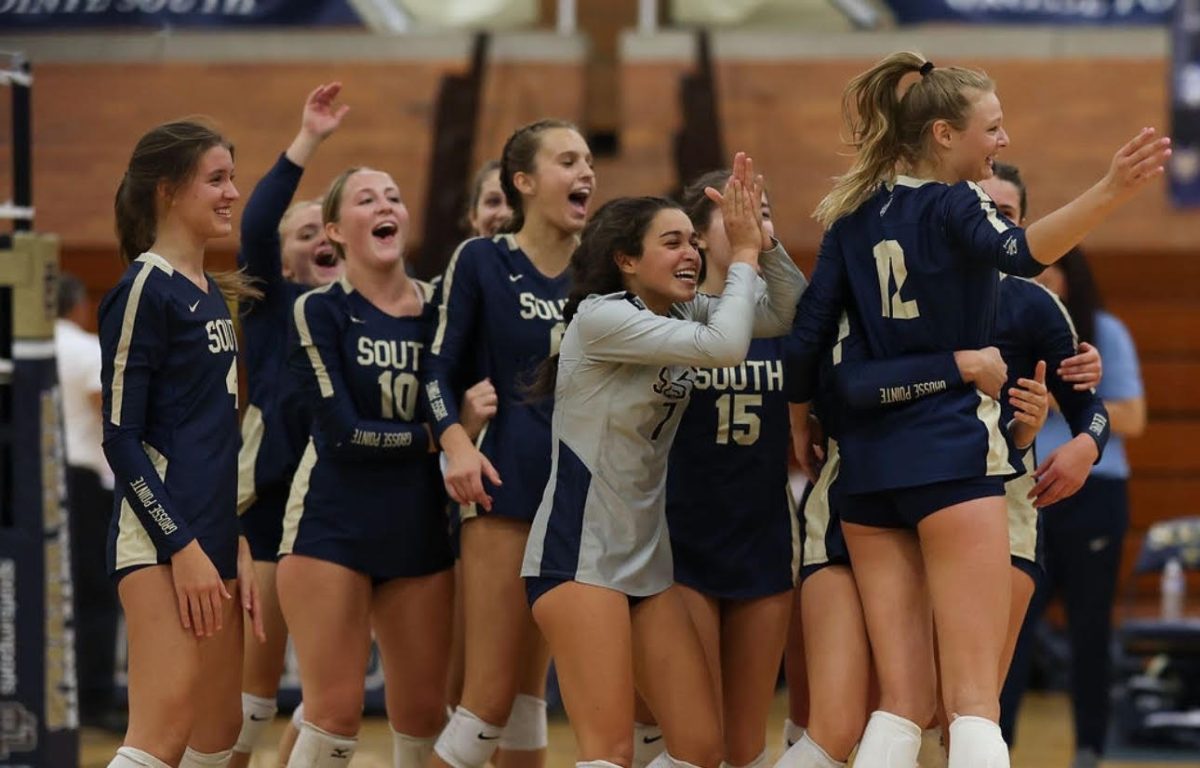 The girls Varsity Volleyball team celebrates after a win against cross-town rival, Grosse Pointe North.