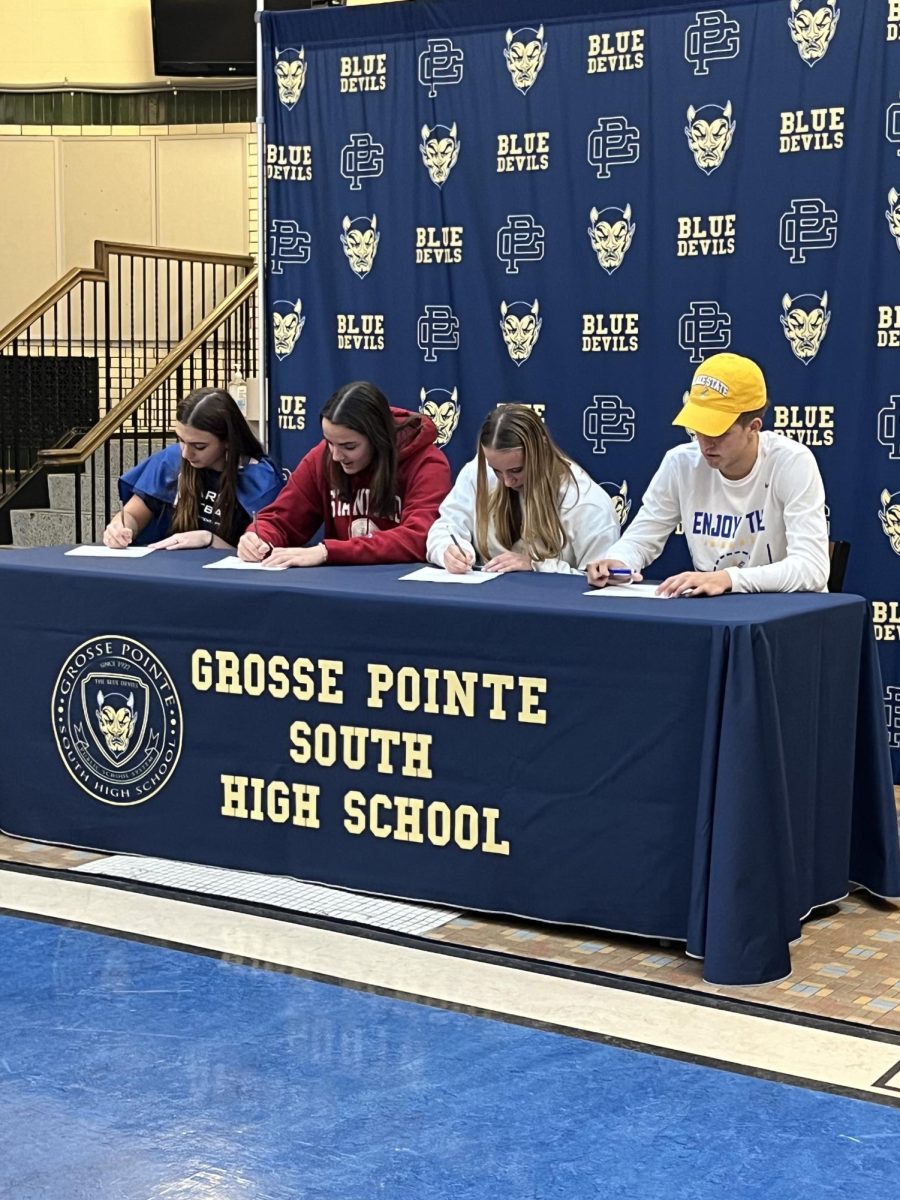 Four eager students sign their papers to take their athletics to the collegiate level 
