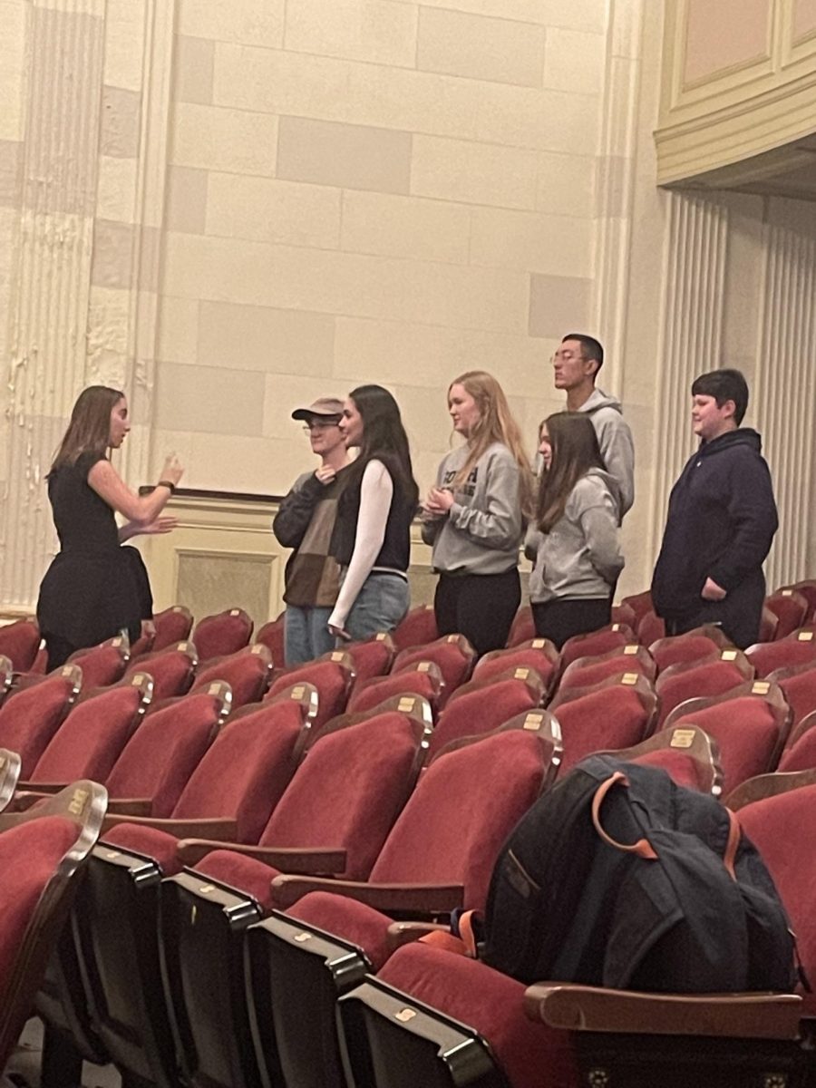 Ella Johnson ’24 giving directions on a warm-up exercise during auditions to the aspiring young actors and actresses in front of her.