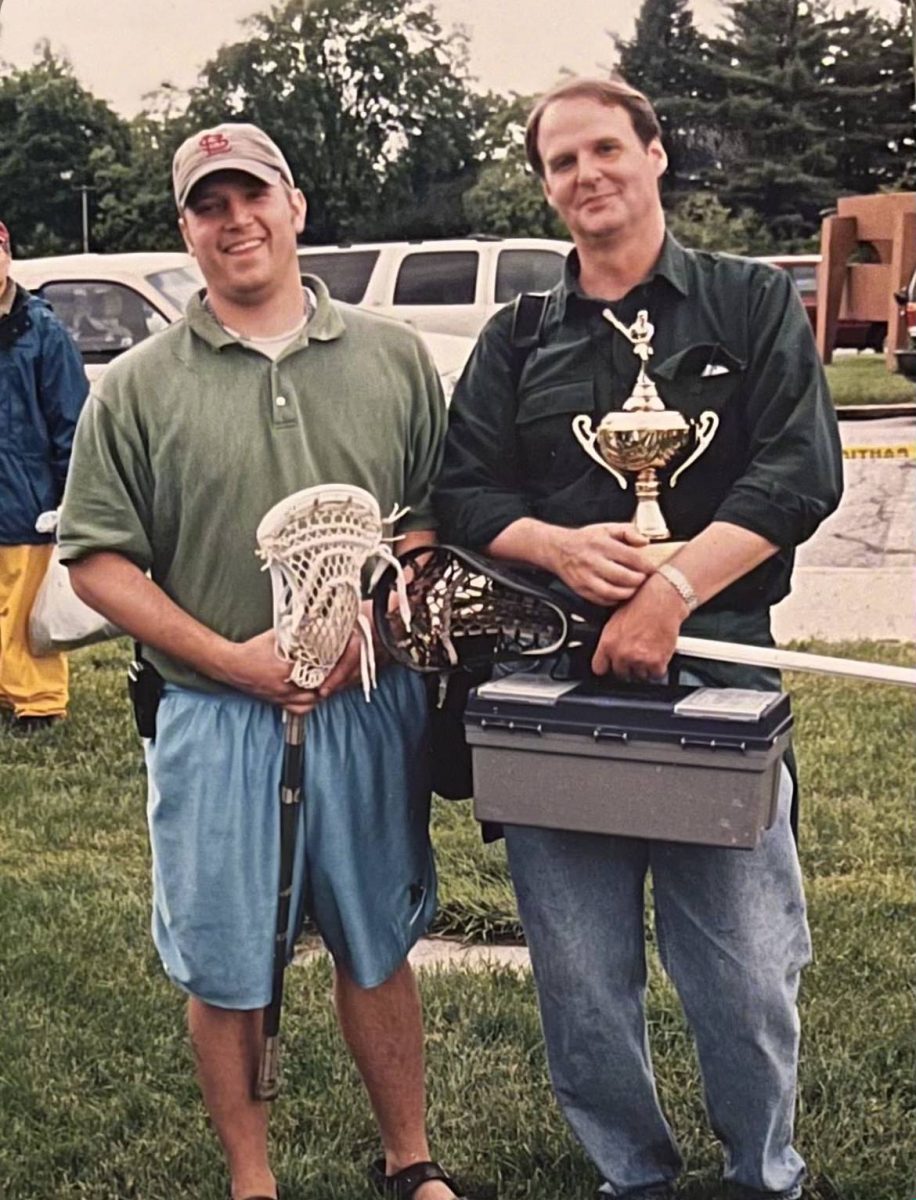Head coach Shaun Hampton (left) and his father (right) contently holding the 2019 Girls Lacrosse State Championship Trophy for Grosse Pointe North. 