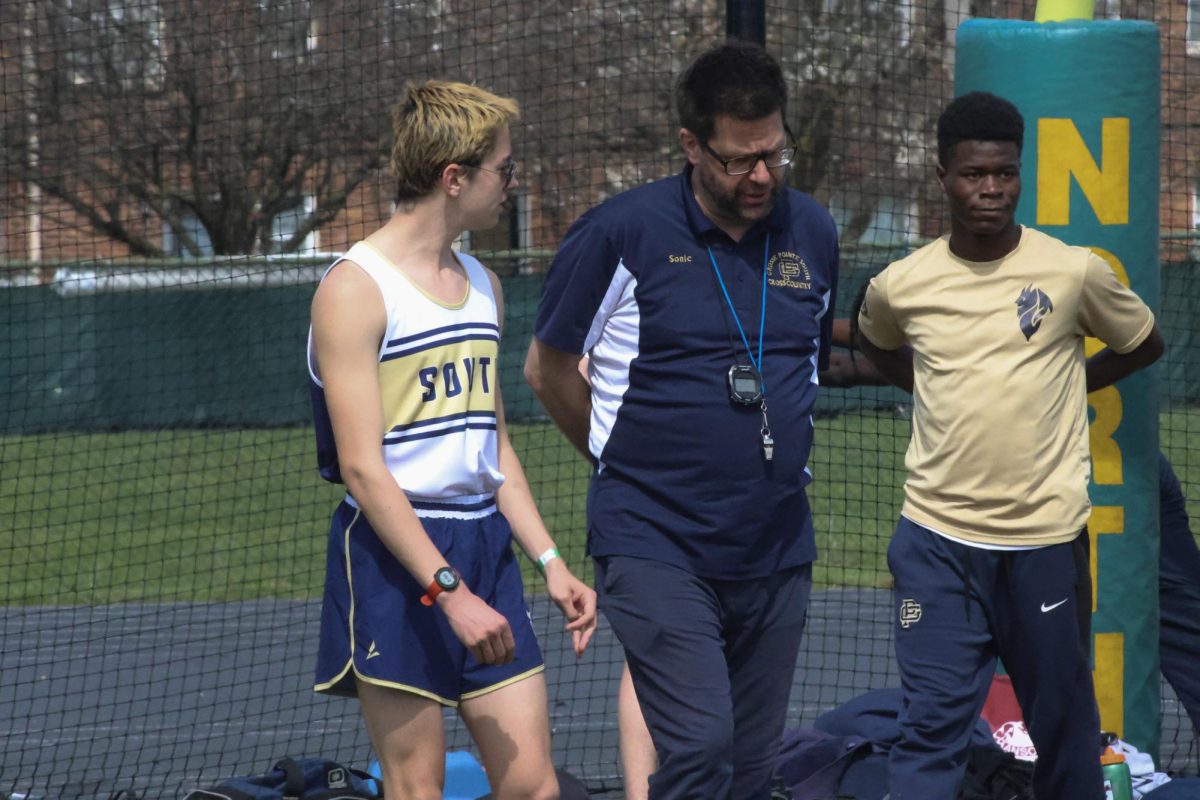 Coach Mark Sonnenberg talks to Brody Fitzgibbon ’25 during the track meet against Grosse Pointe North, strategizing Fitzgibbon’s upcoming races. Fitzgibbon later ran a personal record in the 1600m race.