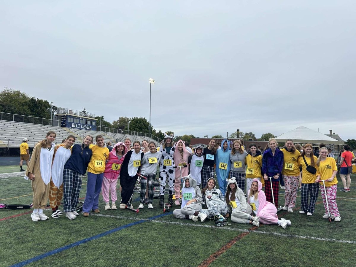 The field hockey team prepares for their 5k while dressed in onesies/pajamas with scooters and roller blades.