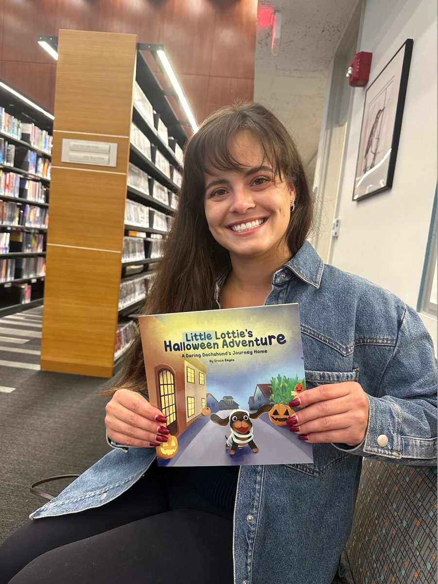 Grace Reyes holds a copy of her freshly completed children’s book, “Little Lottie’s Halloween Adventure.”