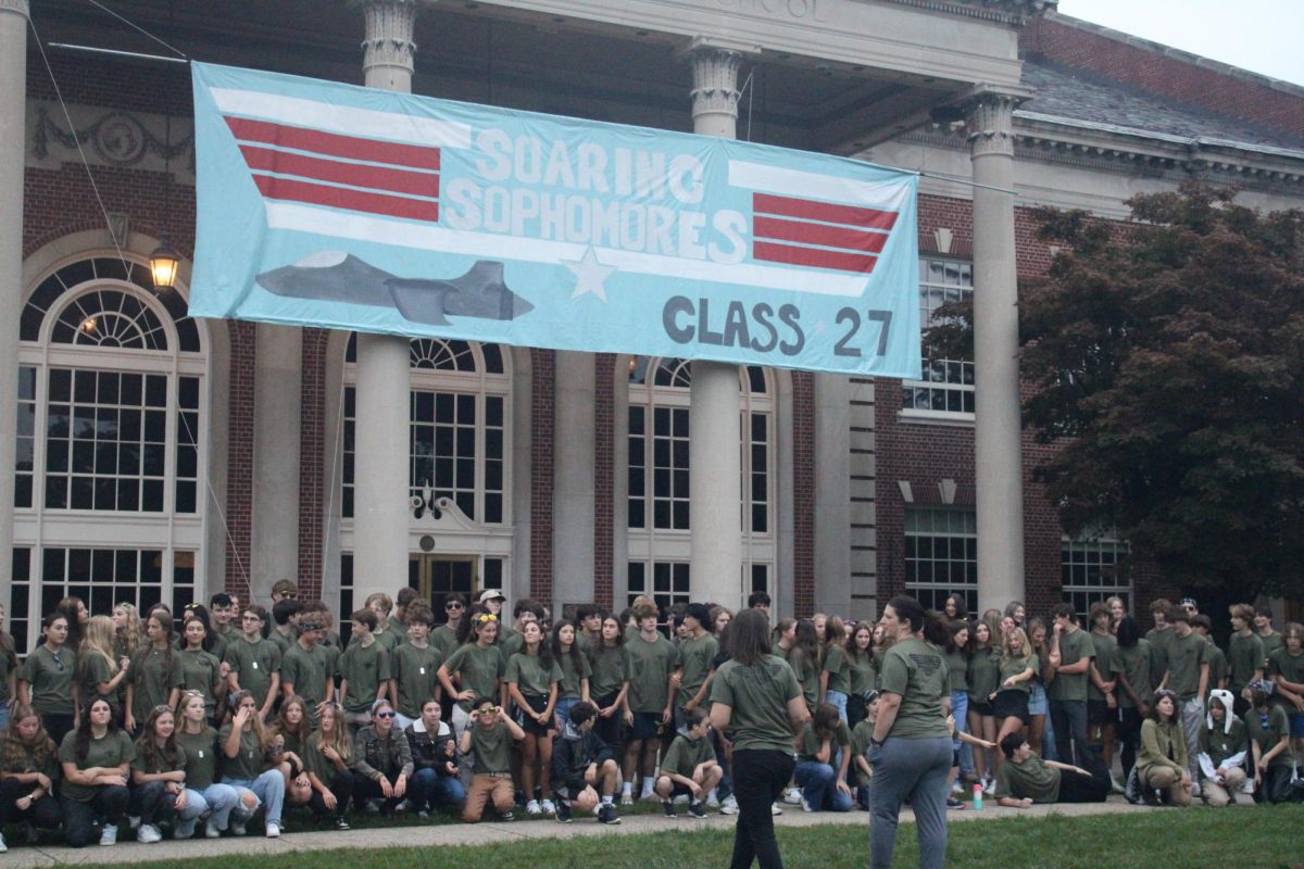 Class advisors usher the sophomores to squeeze in for the class photo with the banner.