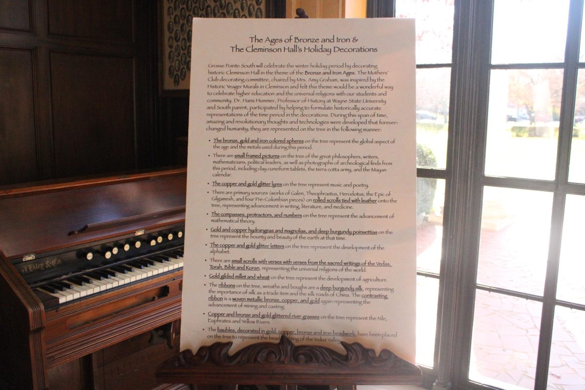 A large sign sits in Cleminson Hall explaining the significance of the room’s historically accurate tree and its ornaments, themed around the Bronze and Iron Ages. Located just to the left of the large tree, it reads, “The Age of Bronze and Iron & The Cleminson Hall’s Holiday Decorations.”