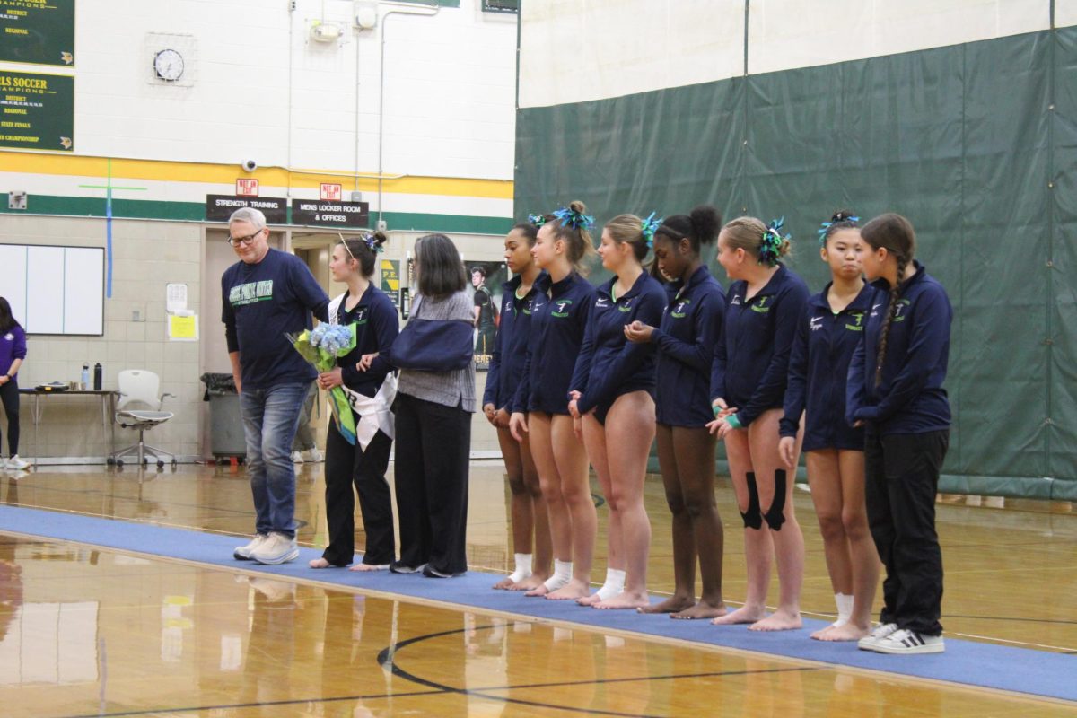 Lucy Tull ’25 is escorted by her parents during the Grosse Pointe United Gymnastics teams Senior Night.