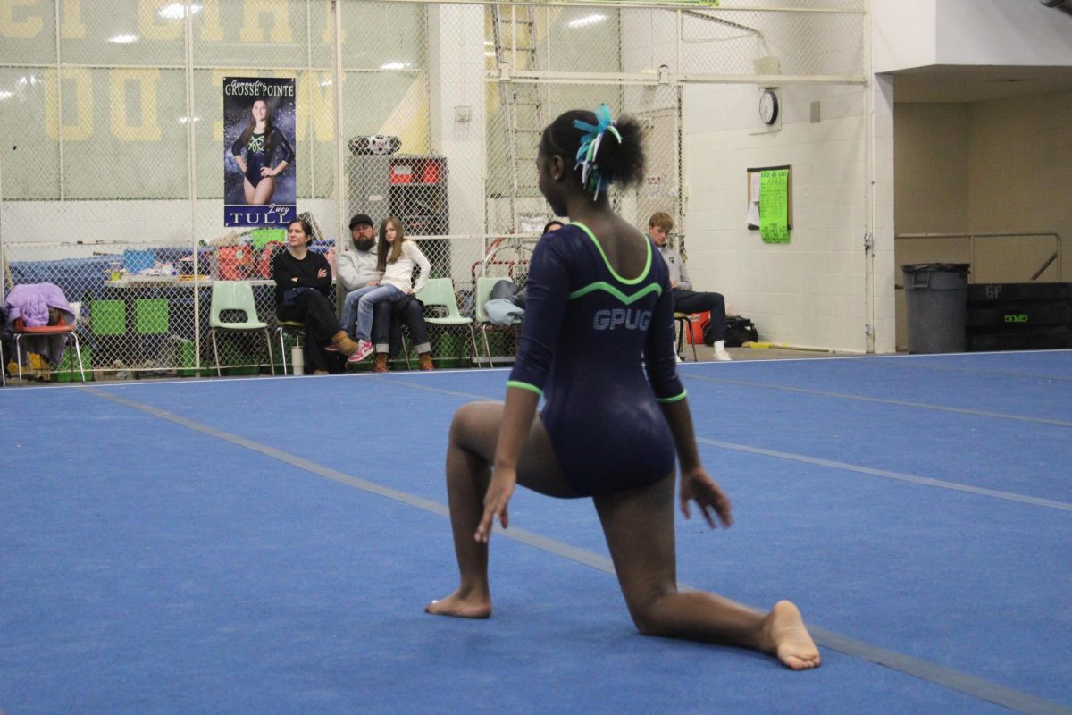 North United Gymnastics team member Ahmirah Green ’28 kneels as she prepares to tackle her updated floor routine in the evening's meet against Rochester Hills.