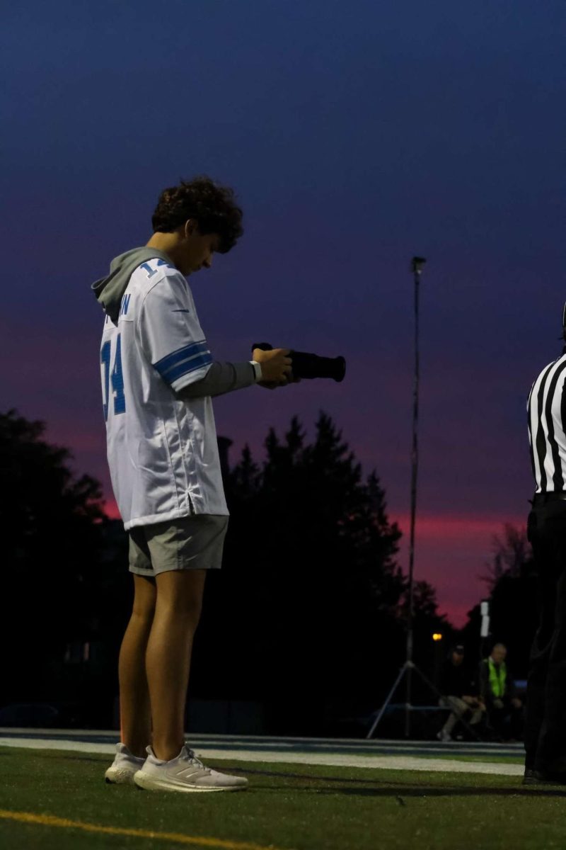 Charlie Thomas, GPS Devils Den graphic designer, capturing photos of the Sept. 27, 2024 varsity football game against Roseville at Grosse Pointe South stadium.