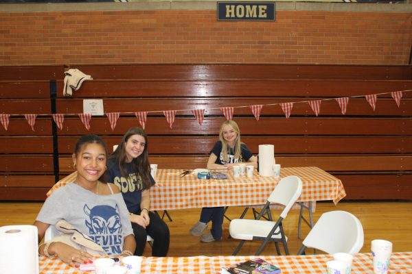 Creativity arises: Sabine Kivland-Stackhouse, Lauren Cole and Reese Straske, all '27, take charge of the face painting station and practice popular face paint designs before kids arrive. 