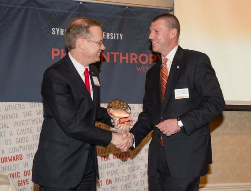 Kent Syverud, during his time as chancellor of Syracuse University, grants Chris Meek the Orange Circle Award for his philanthropic work. 
