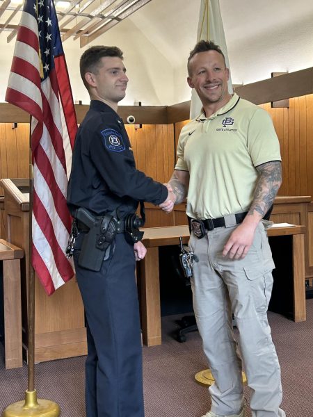 Earning the badge: Former South student, Paul Lyke shakes hands with South resource officer Jim LaBeau at the Farms police station. On May 20, Lyke was sworn into the Farms police after graduating from the police academy on May 18. He was offered a job before entering the academy and plans to work there for many years. Photo courtesy of: Kassiani Norris